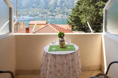 a table with two glasses and a cactus on a balcony at Apartments & Rooms Jelka in Kotor
