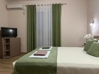 a bedroom with a bed with green curtains and a television at Moonlight Apartments in Ulcinj