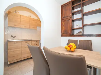a kitchen with a table with chairs and a bowl of fruit at Apartments Elena in Tivat