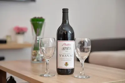 a bottle of wine and two wine glasses on a table at Apartment Atina in Kotor