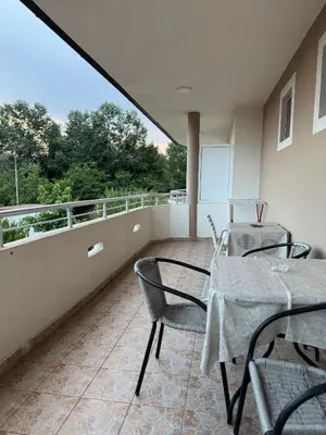 a balcony with two tables and chairs and a view of trees at Studio Apartments Domenik in Ulcinj