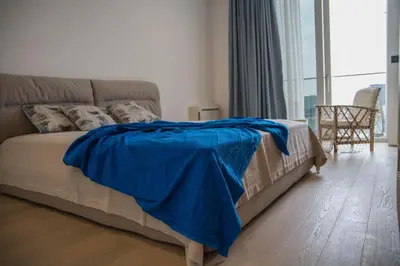 a bedroom with a bed with a blue blanket on it at Leona Residences Apartment in Budva