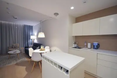 a kitchen and living room with white cabinets and a table at Leona Residences Apartment in Budva
