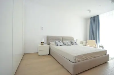 a white bedroom with a large bed with blue pillows at Leona Residences Apartment in Budva