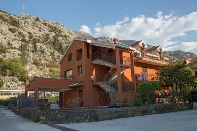 a building with balconies and stairs in front of a mountain at Apartment Damjan in Kotor