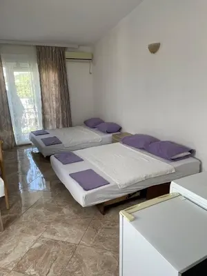 three beds in a room with purple pillows at Apartments Neda in Sutomore