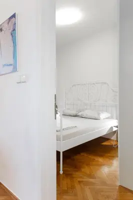 a white bed in a white room with wooden floors at Old town Beauty Apartment with great view in Podgorica