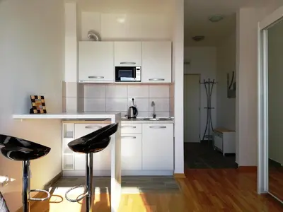 a kitchen with white cabinets and black stools at Apartment Olive Montenegro KO Becici in Budva