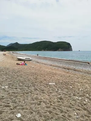 a person laying on a beach next to the water at Guest House Radulovic in Petrovac na Moru