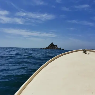 a boat in the ocean with a rock in the distance at Guest House Radulovic in Petrovac na Moru