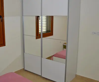 a wardrobe with glass doors in a room at Guest House Radulovic in Petrovac na Moru