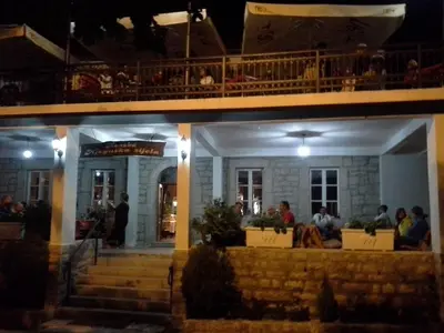a group of people sitting outside of a building at night at BNB Njeguska sijela in Njeguši