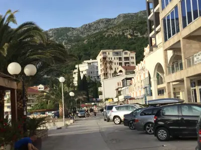 a city street with parked cars and a mountain at Apartment Sunset in Rafailovici