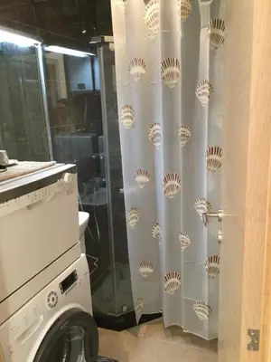a shower curtain in a bathroom with a washing machine at Apartment Sunset in Rafailovici