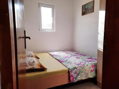 a small bed in a room with a window at Apartmani na moru in Bar