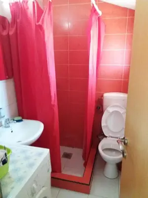 a bathroom with a toilet and a sink with pink shower curtain at Apartmani na moru in Bar