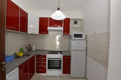 a small kitchen with red cabinets and white appliances at Lux Apartments Kristina in Budva