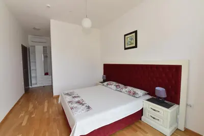 a bedroom with a bed with a red headboard at Lux Apartments Kristina in Budva