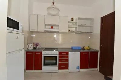 a kitchen with red cabinets and white appliances at Lux Apartments Kristina in Budva