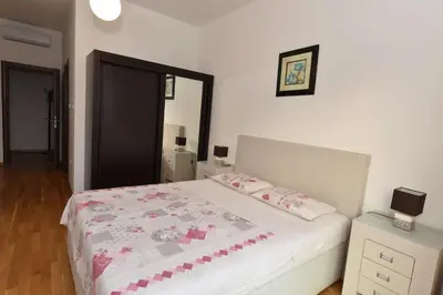 a bedroom with a white bed with pink and white sheets at Lux Apartments Kristina in Budva
