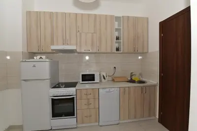 a kitchen with white appliances and wooden cabinets at Lux Apartments Kristina in Budva