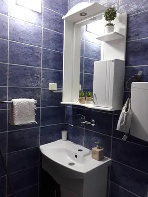 a blue tiled bathroom with a sink and a mirror at Apartment Vukasevic in Virpazar