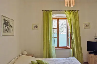 a bedroom with a window with green curtains and a bed at Ribica Apartments in Kotor