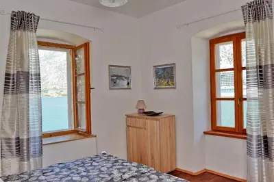 a bedroom with two windows and a bed in it at Ribica Apartments in Kotor
