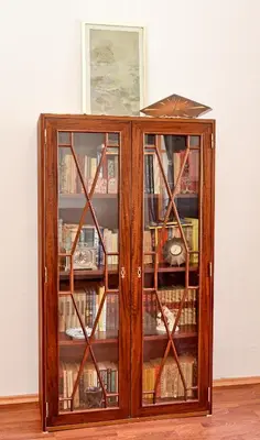 a wooden cabinet with glass doors with books at Ribica Apartments in Kotor
