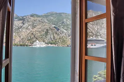 a window view of a body of water with a cruise ship at Ribica Apartments in Kotor