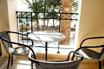 a table and chairs on a balcony with a window at Vasiliki Seaside Apartments in Petrovac na Moru