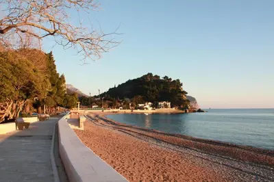 a beach with benches next to the water at Vasiliki Seaside Apartments in Petrovac na Moru