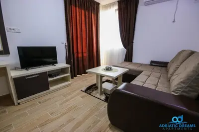 a living room with a couch and a tv and a table at Adriatic Dreams Apartments in Dobra Voda