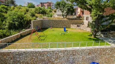 a stone wall with a yard with a playground at Adriatic Dreams Apartments in Dobra Voda