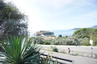 a woman walking down a sidewalk near the water at Vila Mitrovich in Sveti Stefan