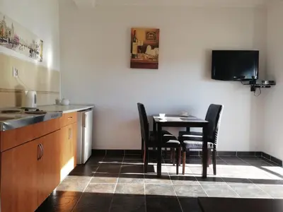 a kitchen with a table and chairs and a tv at Apart Forte Roses Montenegro KO Buljarica in Petrovac na Moru