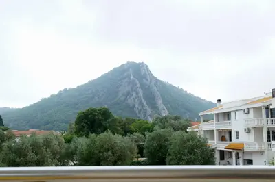 a mountain in the distance with a building and trees at Apart Forte Roses Montenegro KO Buljarica in Petrovac na Moru