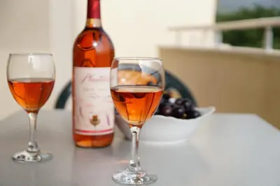 two glasses of wine on a table with a bottle of wine at Apart Forte Roses Montenegro KO Buljarica in Petrovac na Moru