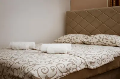 a bed with a headboard and two pillows on it at Apartments Djukic in Tivat