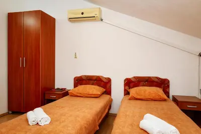 a room with two beds with orange sheets at Apartments Djukic in Tivat