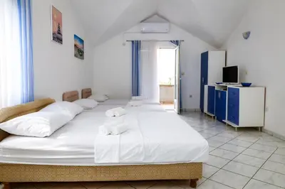 a bedroom with two beds with white sheets and a television at Apartments Djukic in Tivat