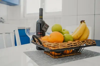 a basket of fruit and a bottle of wine on a counter at Apartments Djukic in Tivat