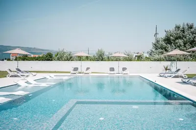 a swimming pool with chairs and umbrellas at Apartments Antique in Ulcinj