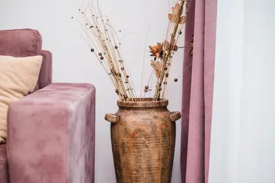 a vase with dried flowers in it next to a couch at Apartments Antique in Ulcinj
