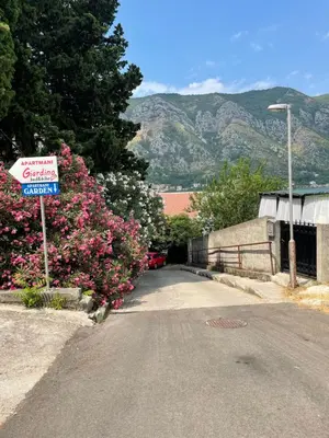 a street with pink flowers and a sign on the side at Apartment Garden in Kotor