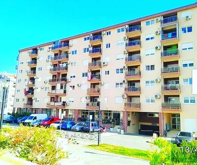 a large apartment building with cars parked in a parking lot at Apartment SVS in Budva