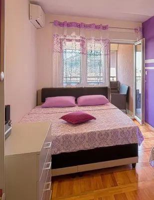 a bedroom with a large bed with pink pillows at Apartment SVS in Budva