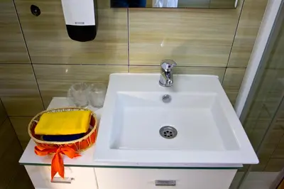 a bathroom sink with a towel and a basket at Apartments Gran Sasso in Ulcinj