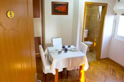 a table and chairs with a white table and a bathroom at Apartments Gran Sasso in Ulcinj