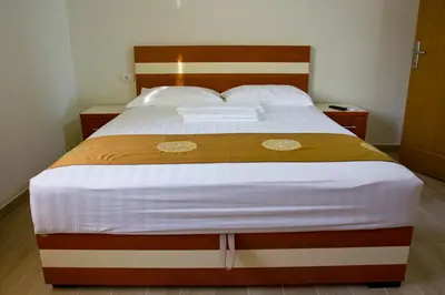 a bedroom with a large bed with a wooden headboard at Apartments Gran Sasso in Ulcinj